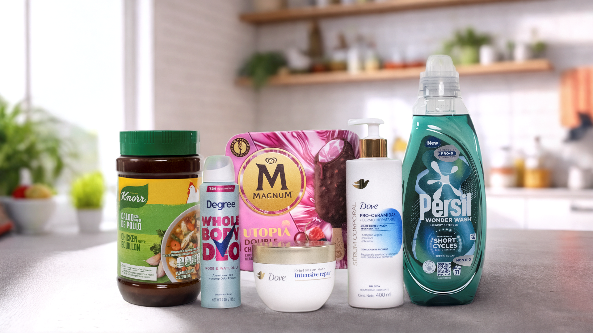 Un assortiment des Marques Puissantes de Unilever disposé sur un plan de travail de cuisine. De gauche à droite, on peut voir un pot de bouillon de poulet Knorr, un spray déodorant Degree portant l'inscription « WHOLE BODY DEO », une boîte de glace Magnum étiquetée « UTOPIA », une bouteille de lait corporel Dove avec sérum pro-céramides, un pot de crème réparation intense Dove et une bouteille de lessive Persil Wonder Wash. À l'arrière-plan, il y a une cuisine moderne avec des plantes et divers objets sur les étagères.