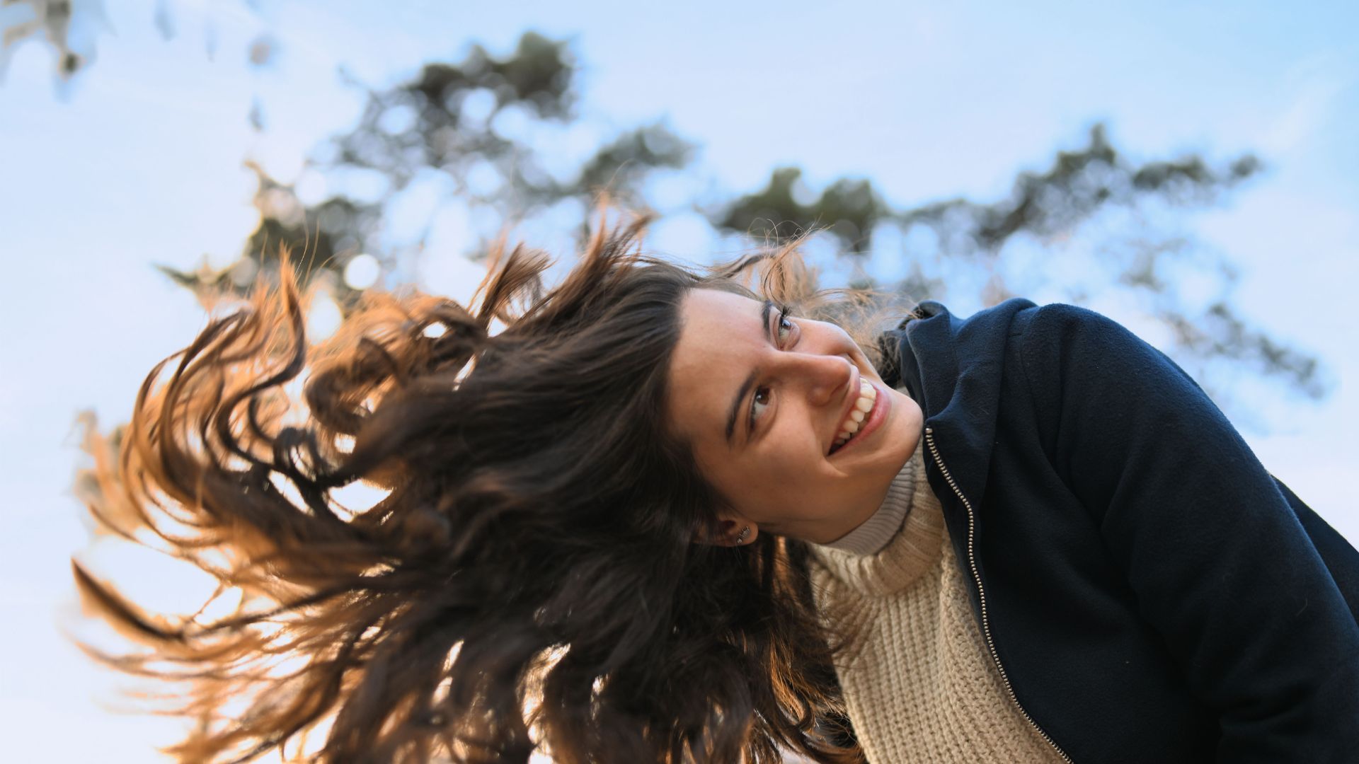 Femme souriante avec les cheveux au vent dans un parc